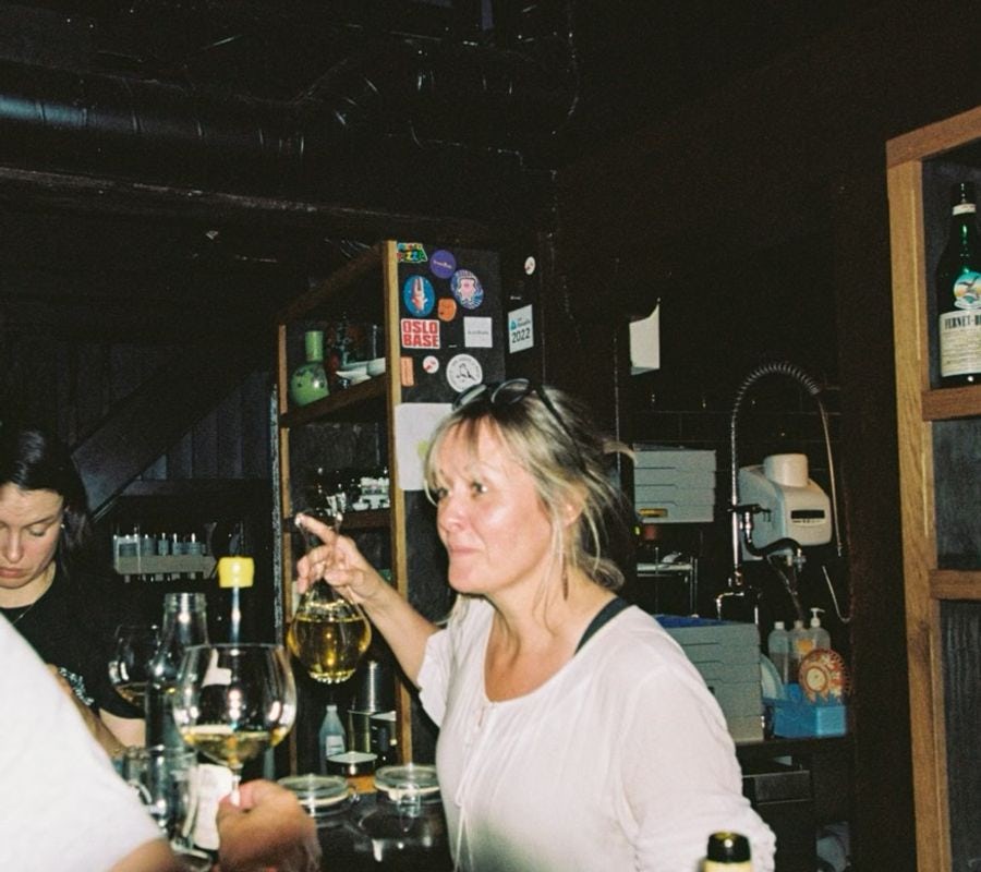 Person behind a bar serving wine to a customer.
